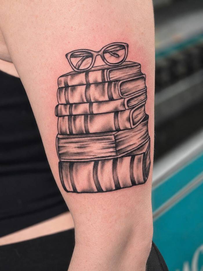 Black and grey stack of books with reading glasses tattoo by Shawn Lowe at Fargo Tattoo in Fargo, North Dakota