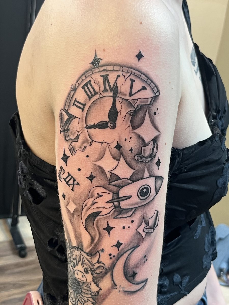 Black and grey forearm tattoo with a clock, rocket, moon, and stars by Shawn Lowe at Fargo Tattoo in Fargo, North Dakota
