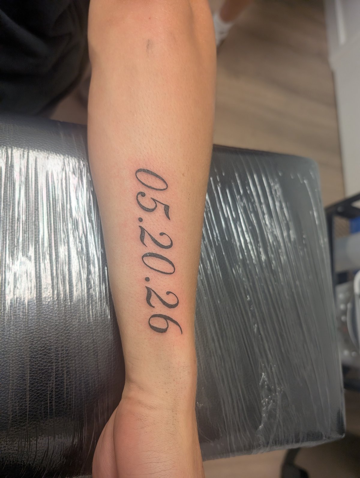 Fine line vertical date script tattoo on the wrist by Shawn Lowe at Fargo Tattoo in Fargo, North Dakota