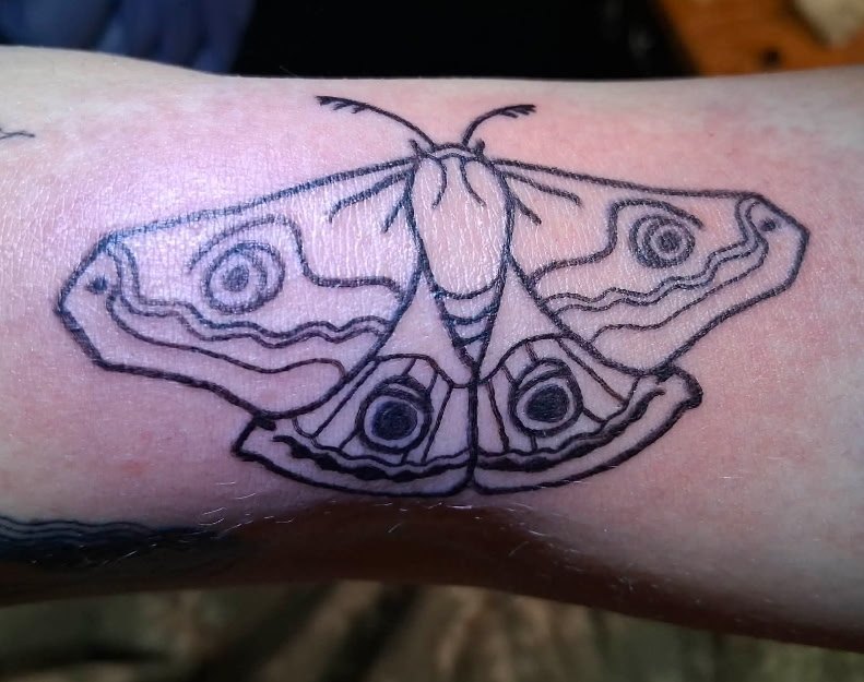 Black ink linework moth tattoo with decorative wing patterns and eye spots by Leni B. at Fargo Tattoo in Fargo, North Dakota