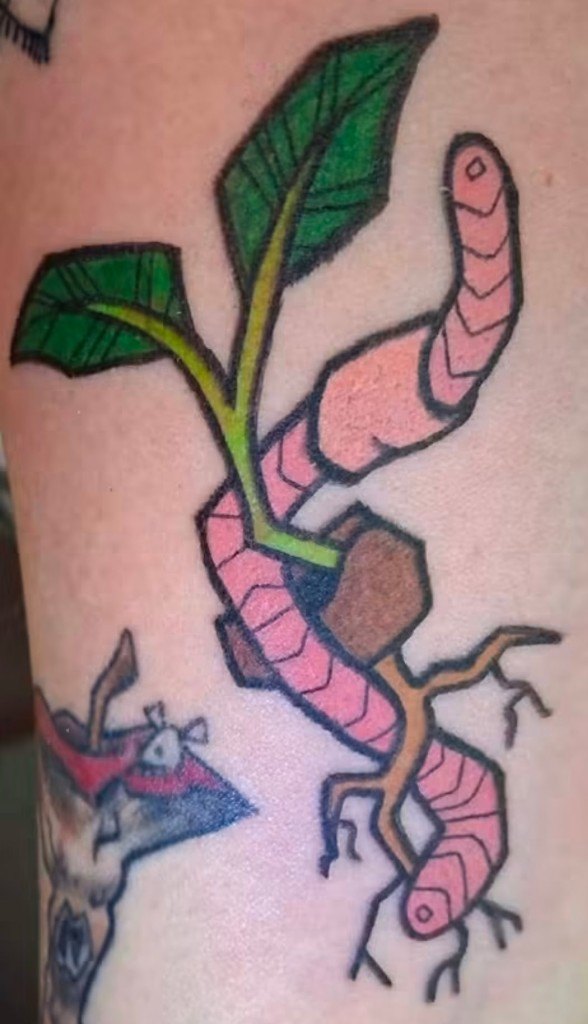 Bright pink illustrative earthworm tattoo intertwined with a small green plant by Leni B. at Fargo Tattoo in Fargo, North Dakota