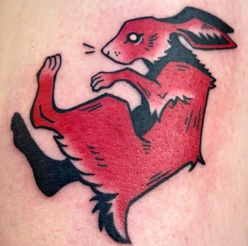 Bold red and black neo-traditional rabbit tattoo in a leaping pose by Leni B. at Fargo Tattoo in Fargo, North Dakota