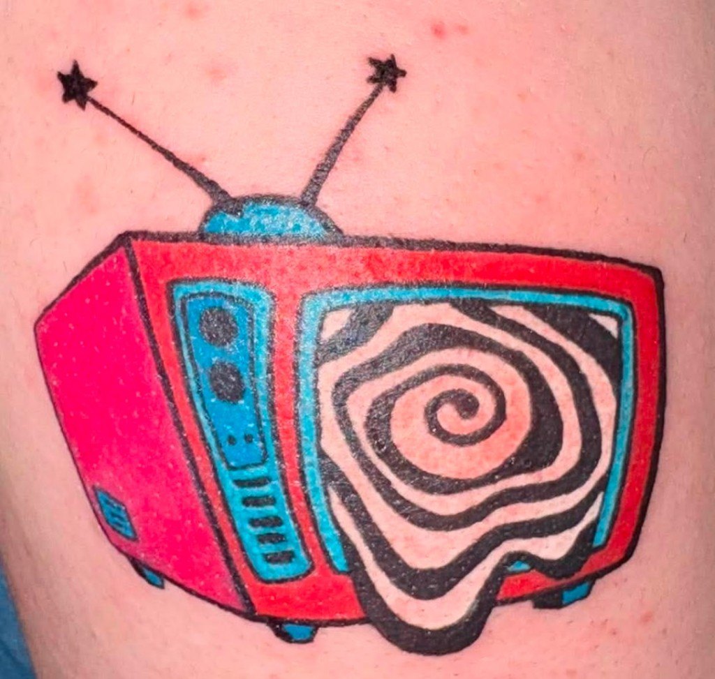Color illustrative tattoo of a retro red television with a hypnotic spiral screen and star-tipped antennas by Leni B. at Fargo Tattoo in Fargo, North Dakota