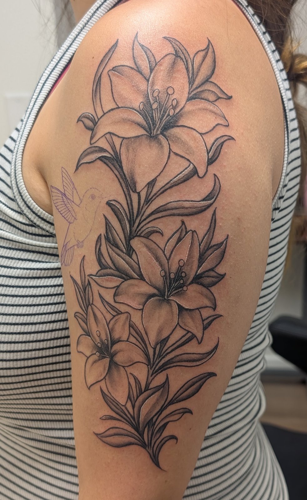 Fine line lily floral tattoo on the upper arm by Shawn Lowe at Fargo Tattoo in Fargo, North Dakota