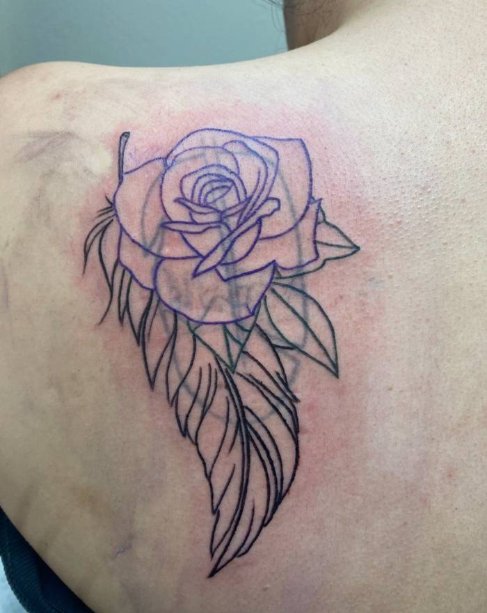 Rose and feather cover-up outline tattooed over faded old ink at Fargo Tattoo