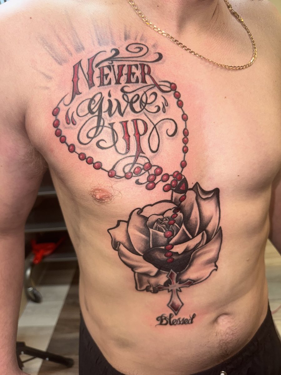 Chest tattoo with a shaded rose, rosary beads, cross, and red accents by Shawn Lowe at Fargo Tattoo in Fargo, North Dakota